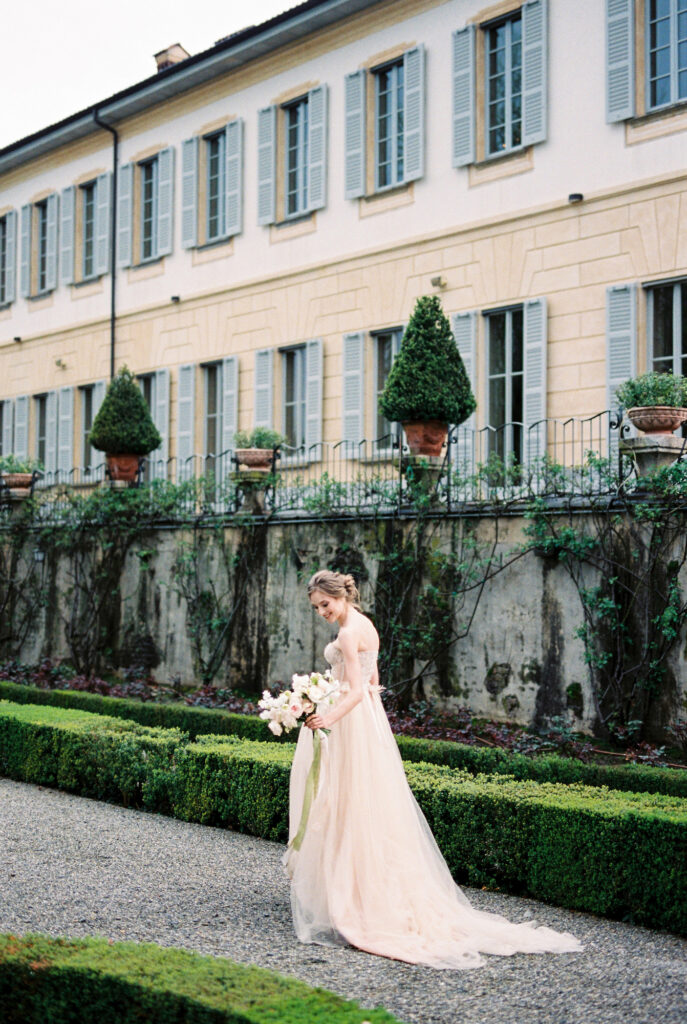 Bride with flowers stands on a path in the park near the old villa. High quality photo